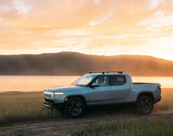 Rivian R1T all-electric pick up truck driving off-road at sunset