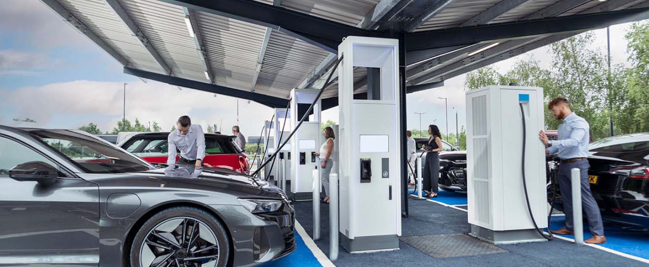 Multiple people charging their electic vehicles standing under a carport