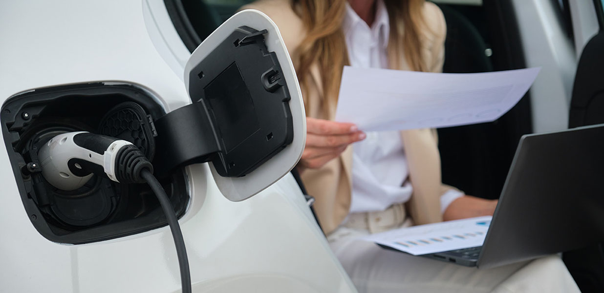 A person holding a paper in front of a charging electric car
