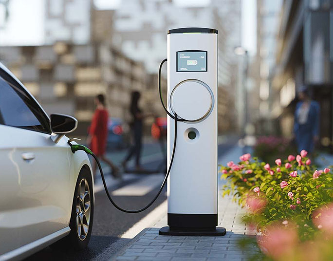 An electric vehicle charging station on a city street with a white car plugged in.