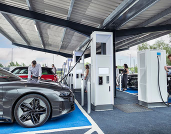 Multiple people charging their electic vehicles standing under a carport