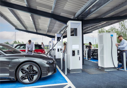 Multiple people charging their electic vehicles standing under a carport