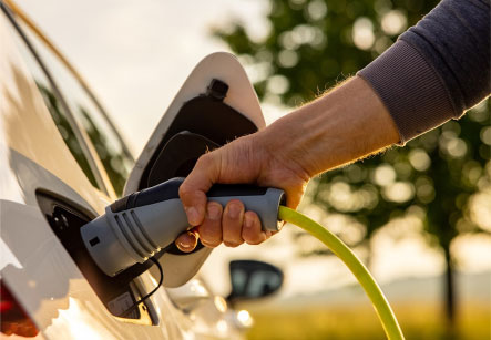 A hand holding the handle of a connected electric vehicle charging cable