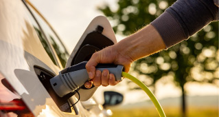 A hand holding the handle of a connected electric vehicle charging cable