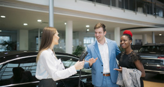 A sales representative showing a charging cable to prospective electric vehicle owners