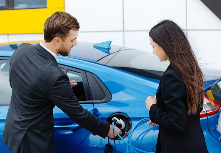 A couple stands outside an electric vehicle while it is charging