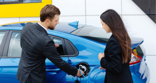 A couple stands outside an electric vehicle while it is charging