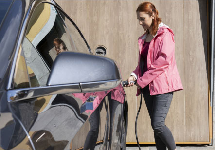 A woman removes the charger from her Subaru electric vehicle