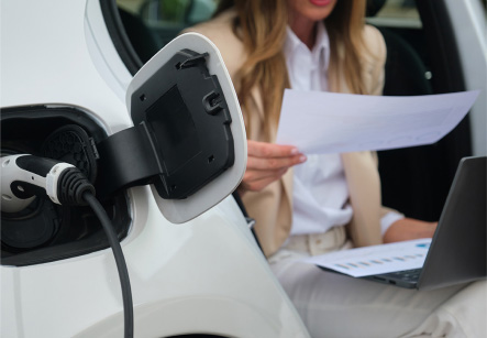 A person holding a paper in front of a charging electric car