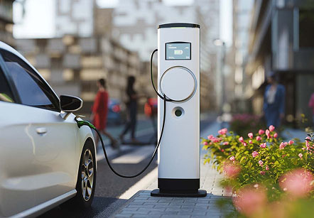An electric vehicle charging station on a city street with a white car plugged in.