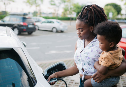 A mother holds her child as she charges her Subaru electric vehicle