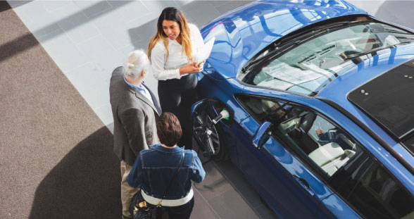 A group of people observing an electric car being charged