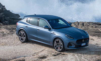 A Maserati Grecale Folgore sits on rocks above a beach