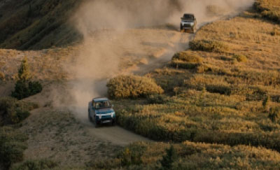 A Rivian off-roads through a dusty trac