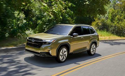 A green Subaru Forester Hybrid SUV driving on a curved road surrounded by dense green trees and vegetation.