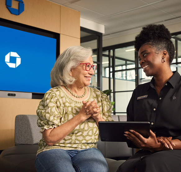 Women sitting on a couch in a Chase branch looking at a tablet.
