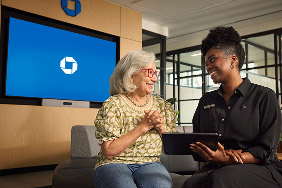 Women sitting on a couch in a Chase branch looking at a tablet.