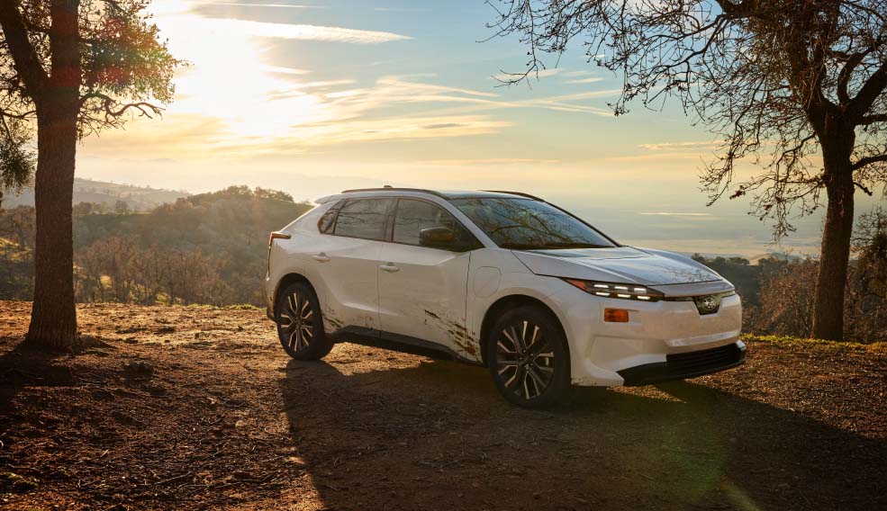 A white Subaru SUV parked on a wooded overlook within a scenic outdoor setting
